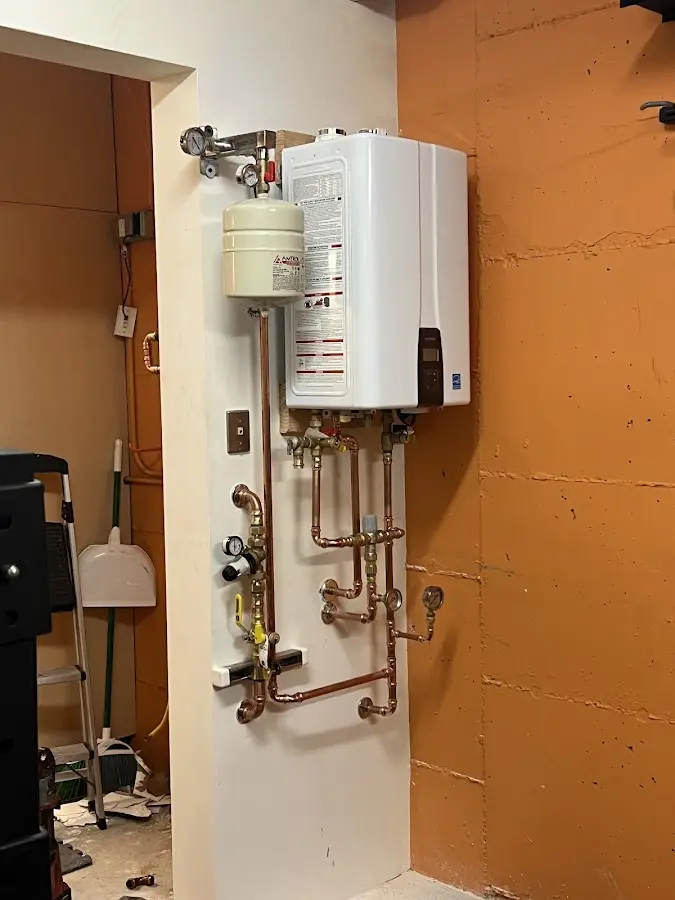 Plumbing technician inspecting water heater connections in Centreville